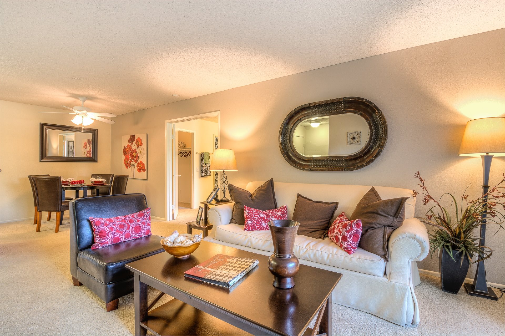 A living room with a black leather chair and a white couch with pink pillows.,A living room with a black leather chair and a white couch with pink pillows.